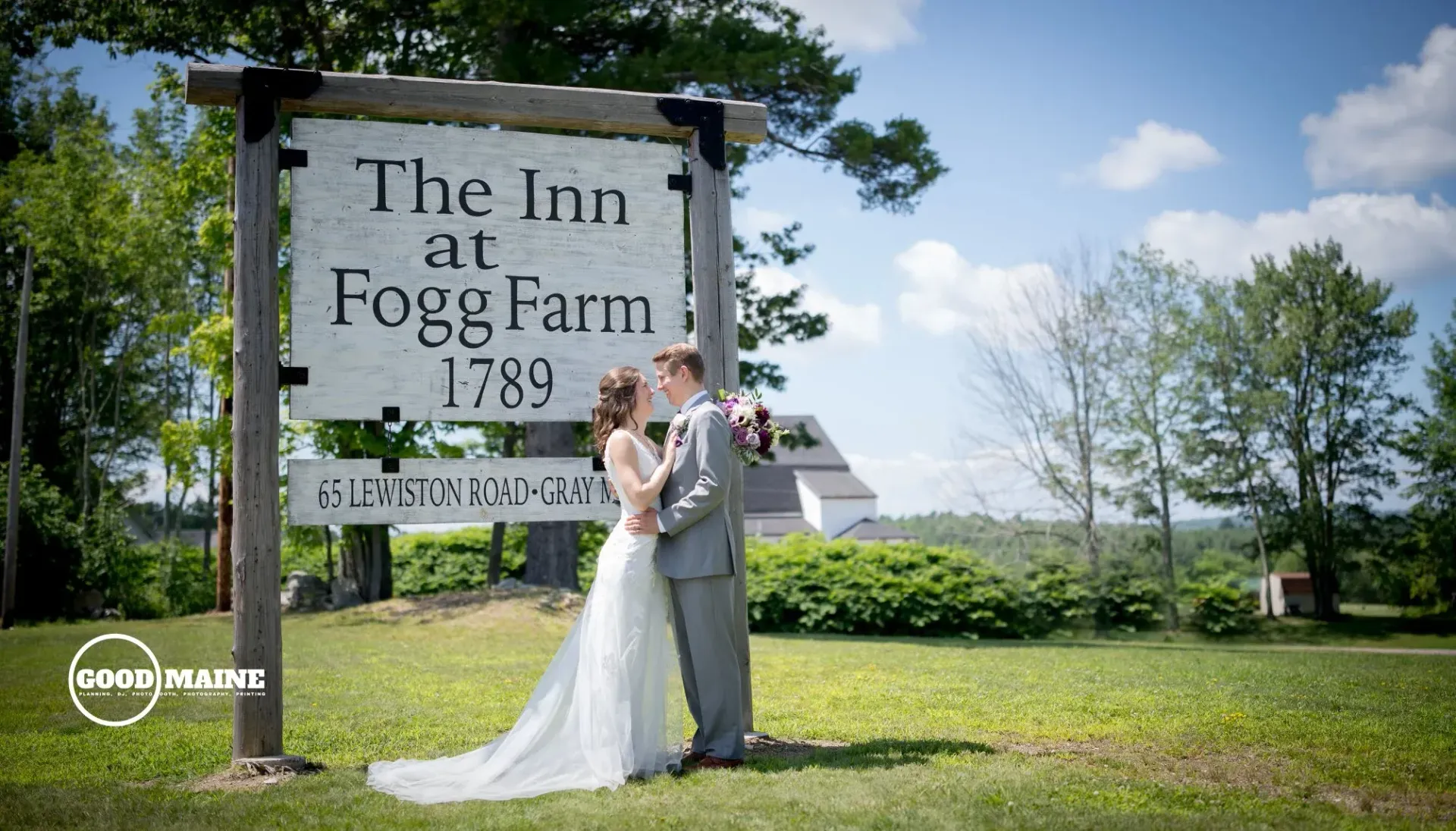 A bride and groom are kissing in front of a sign for the inn at fog farm.
