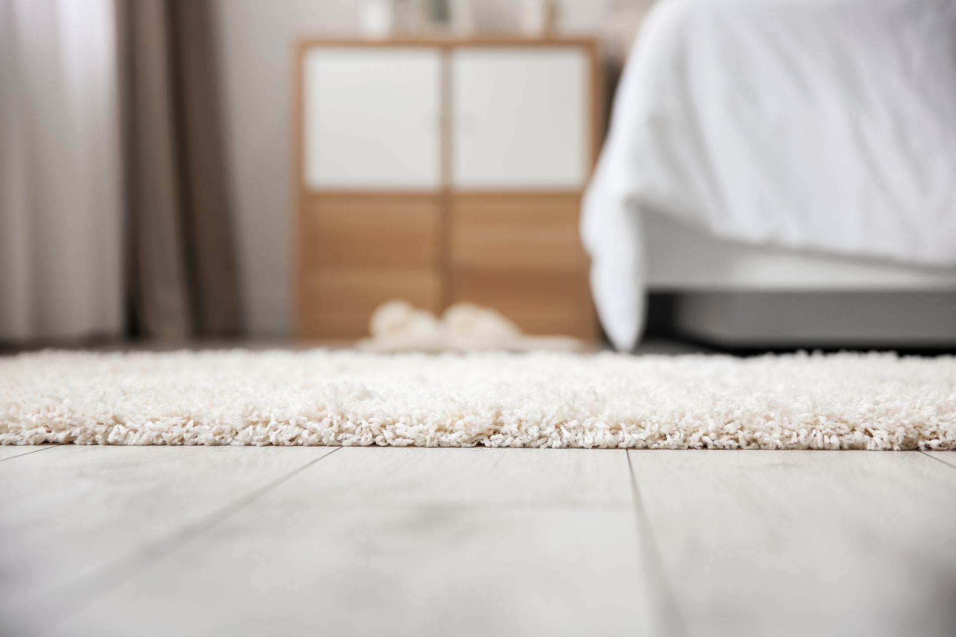 Close-up of a Shaggy White Rug on a Light Wooden Floor in a Bedroom — Magic Mist Carpet Cleaning in Gracemere, QLD