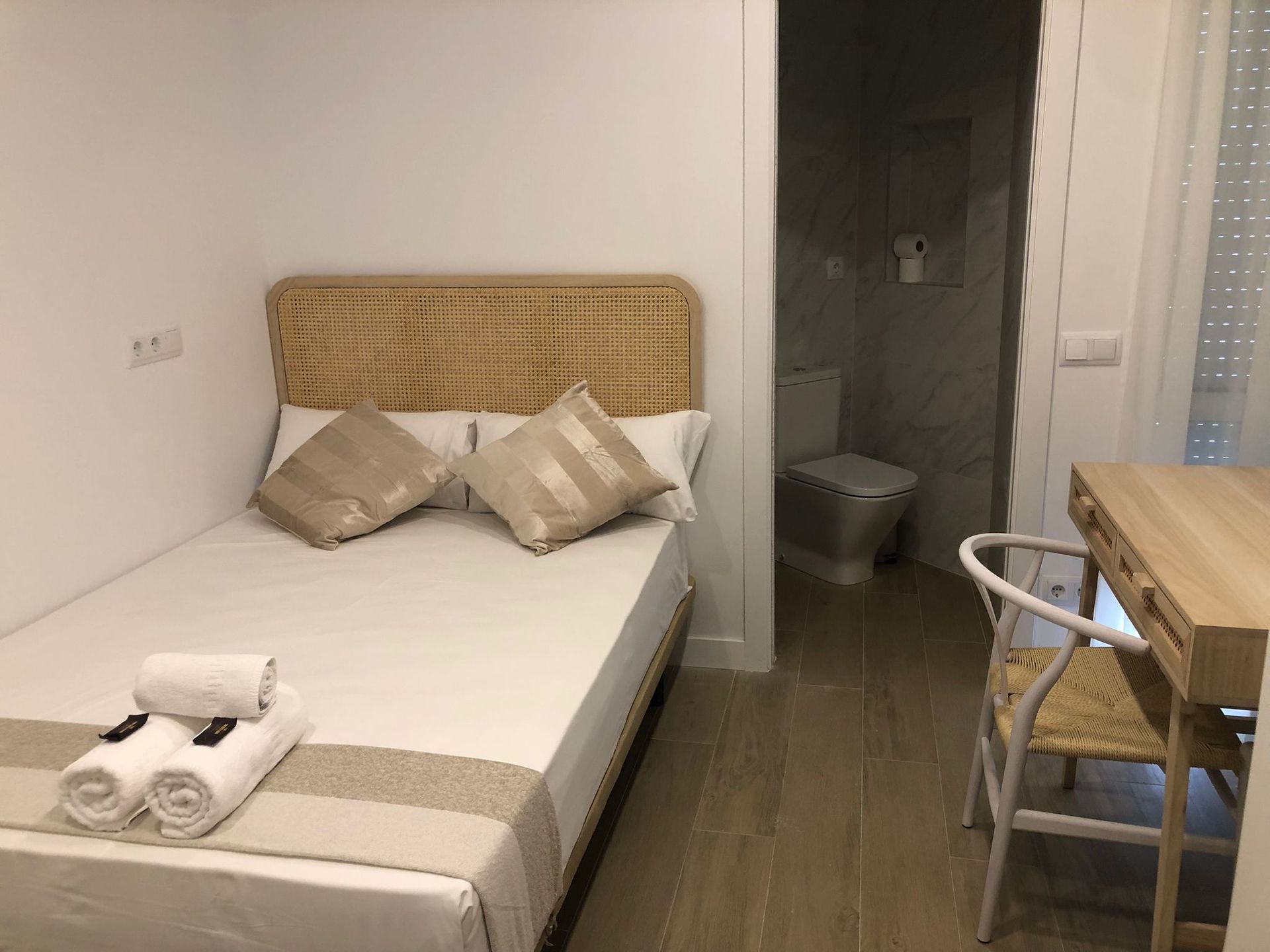 Un dormitorio con una cama, escritorio, silla y baño.