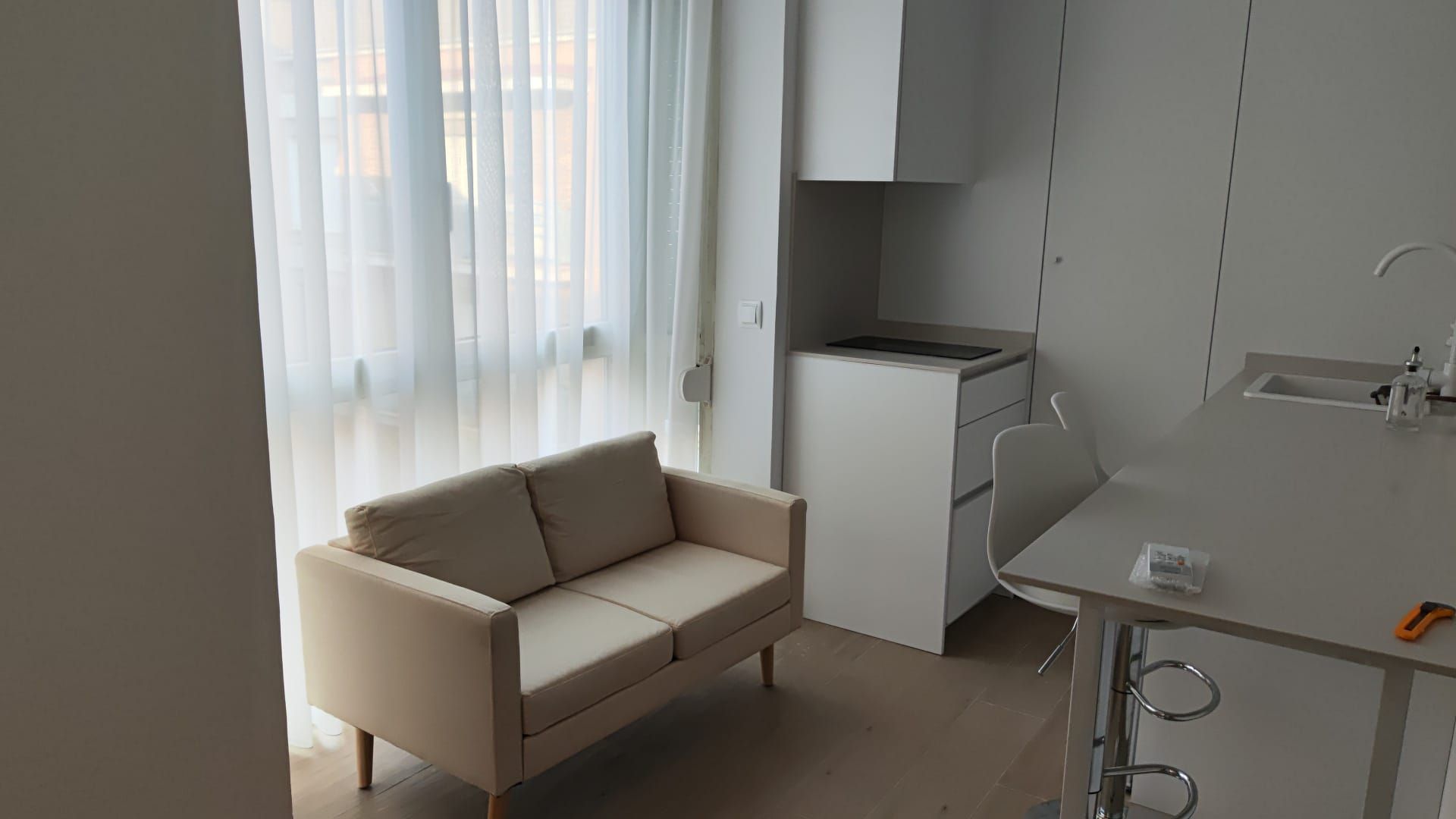 Una sala de estar con sofá, mesa y ventana.