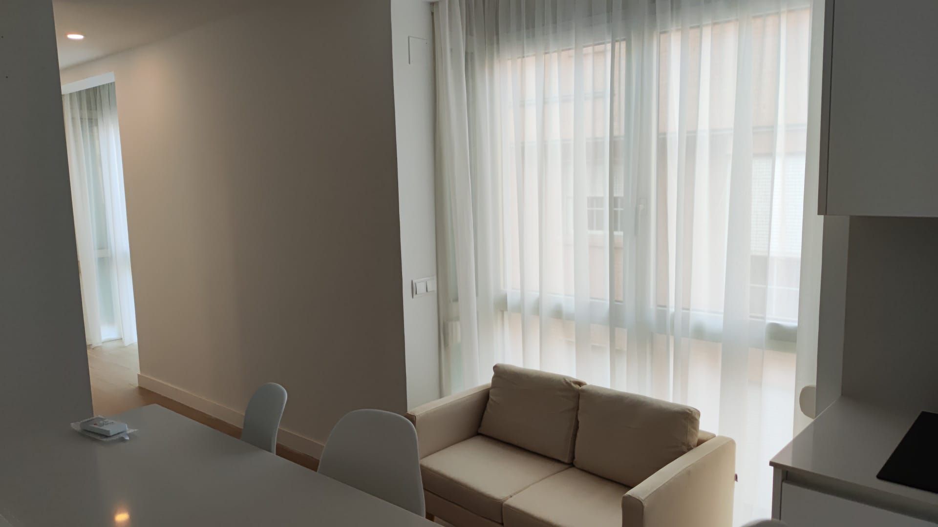 Una sala de estar con sofá, mesa, sillas y cortinas.