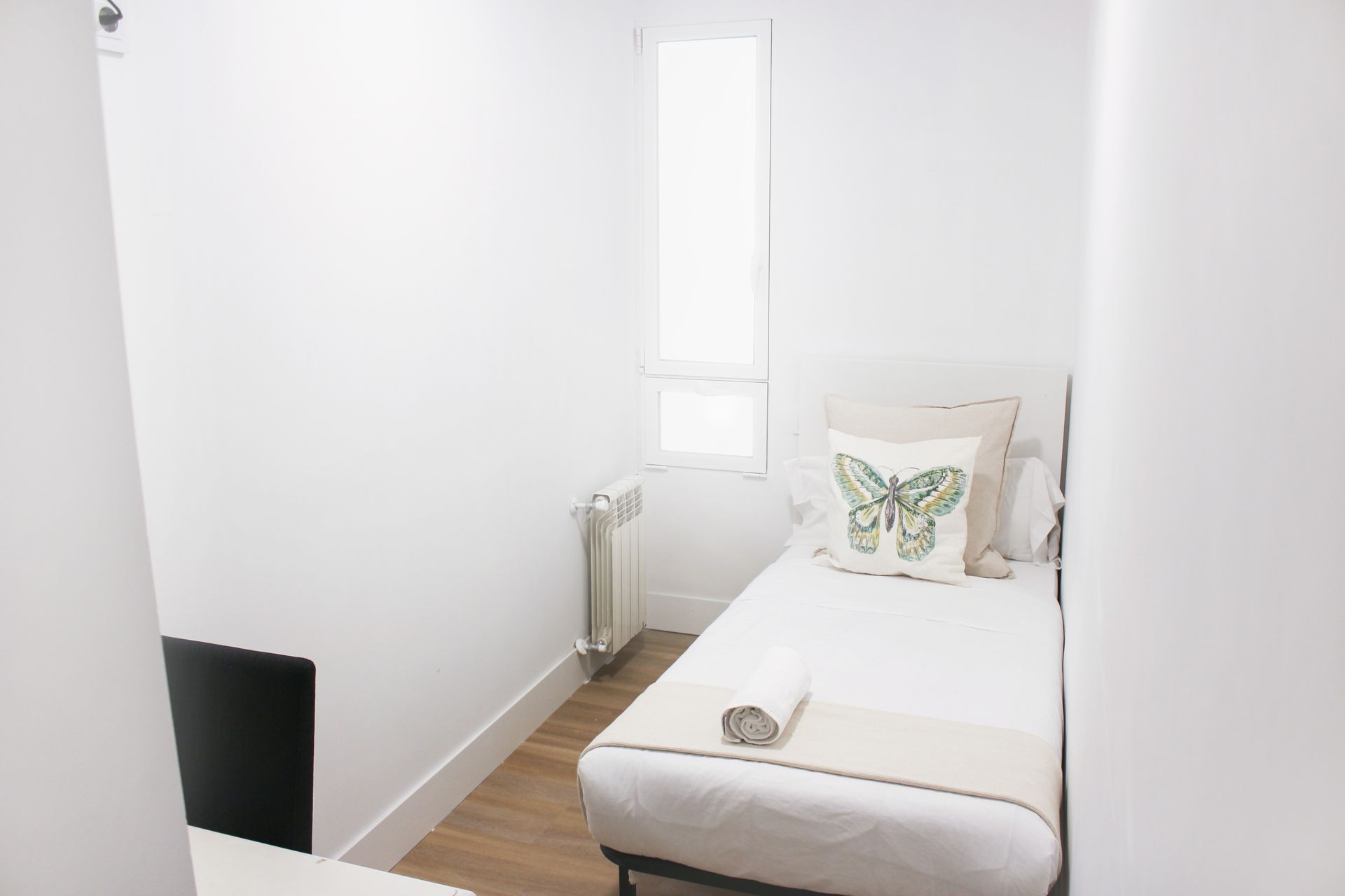 Un dormitorio con una cama individual y una almohada de mariposa.