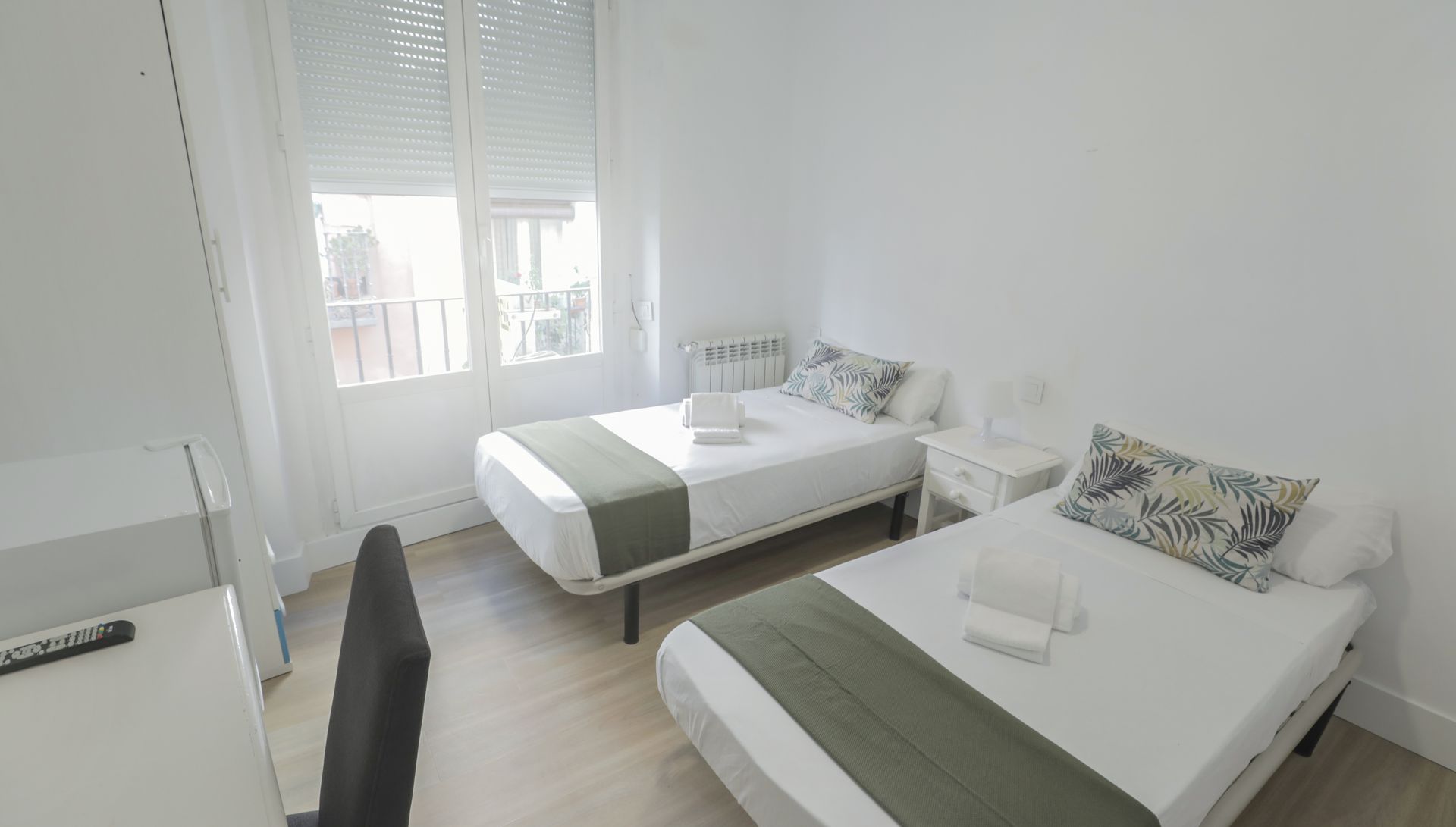 Un dormitorio con dos camas, un escritorio y una ventana.