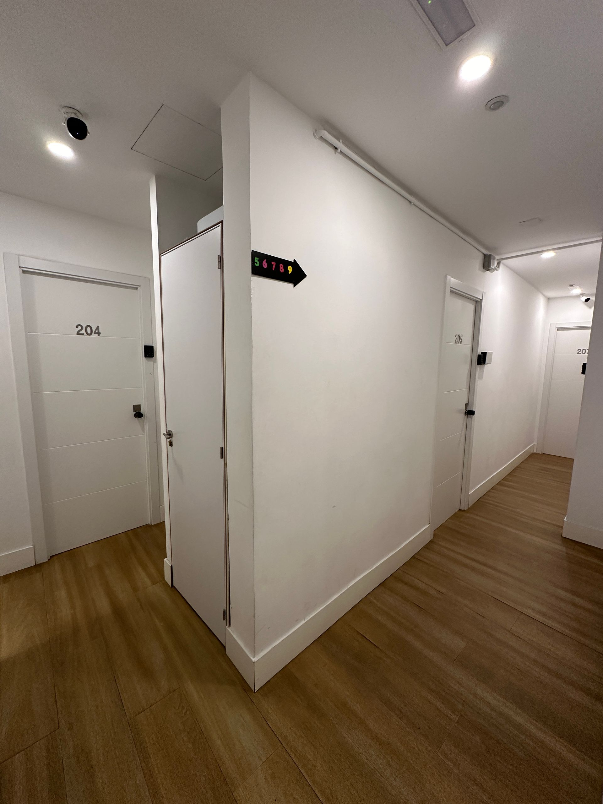 Un largo pasillo con suelo de madera y paredes blancas.