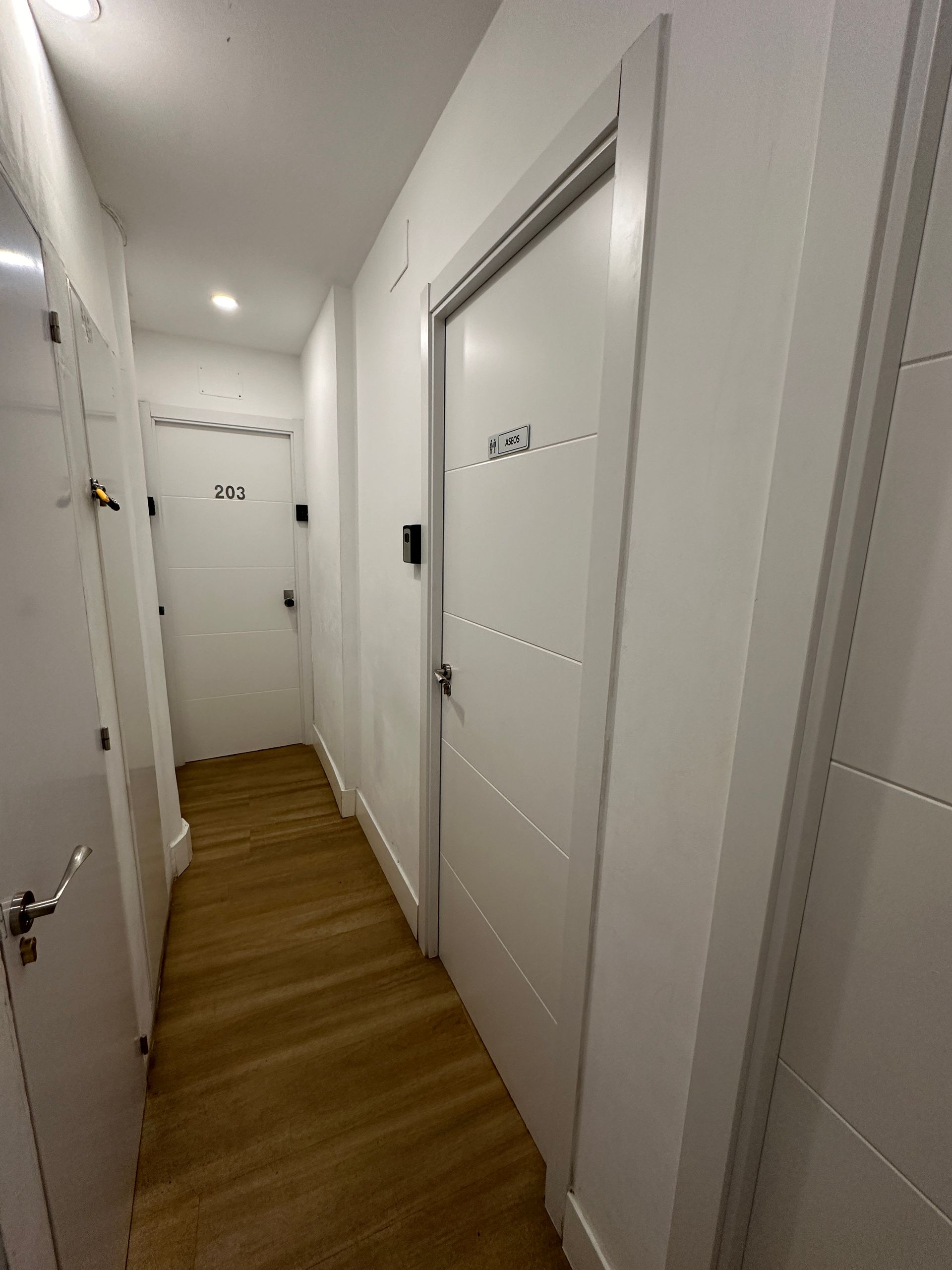 Un largo pasillo con puertas blancas y pisos de madera.