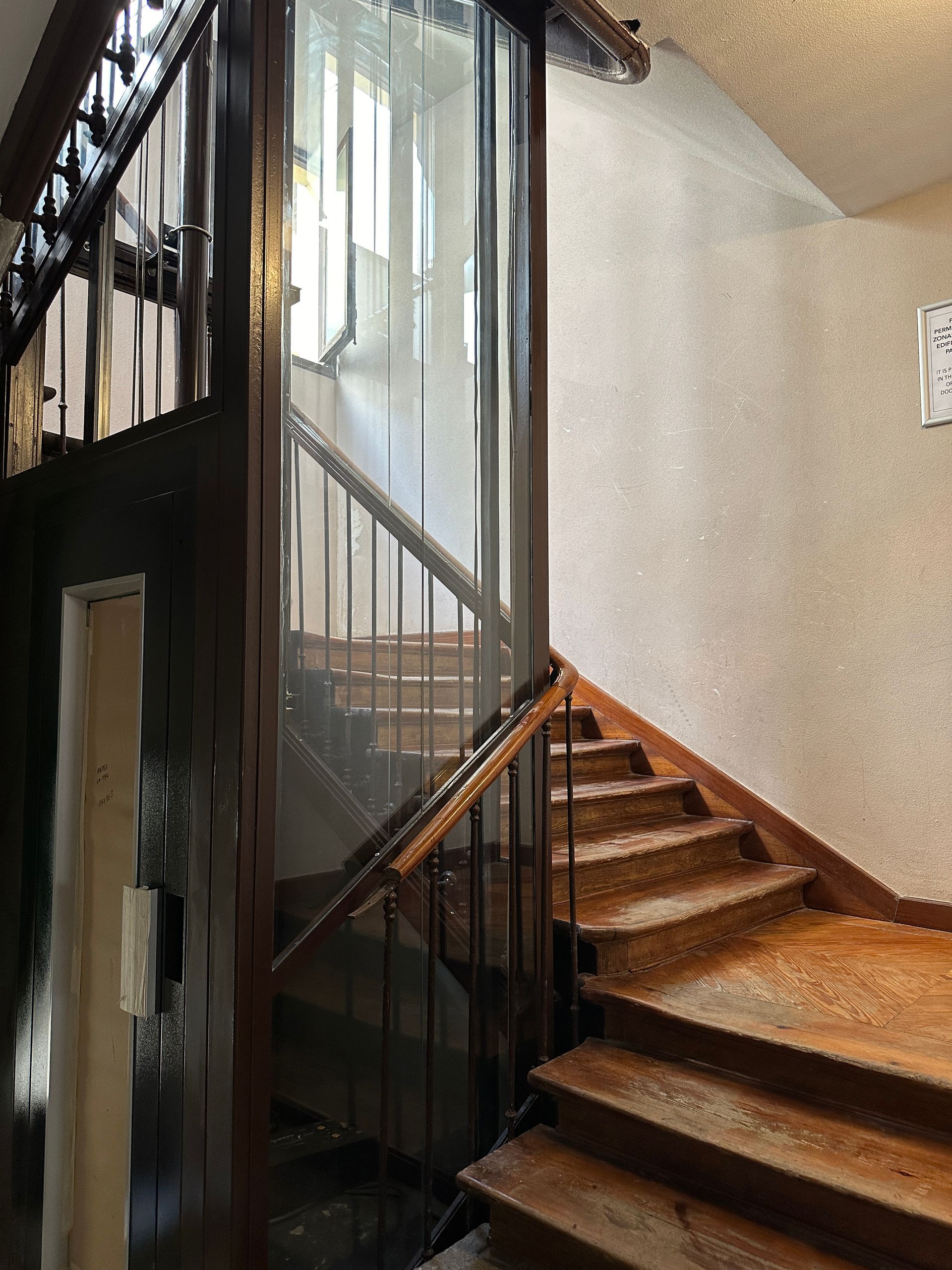 Una escalera con escalones de madera y una puerta de cristal.