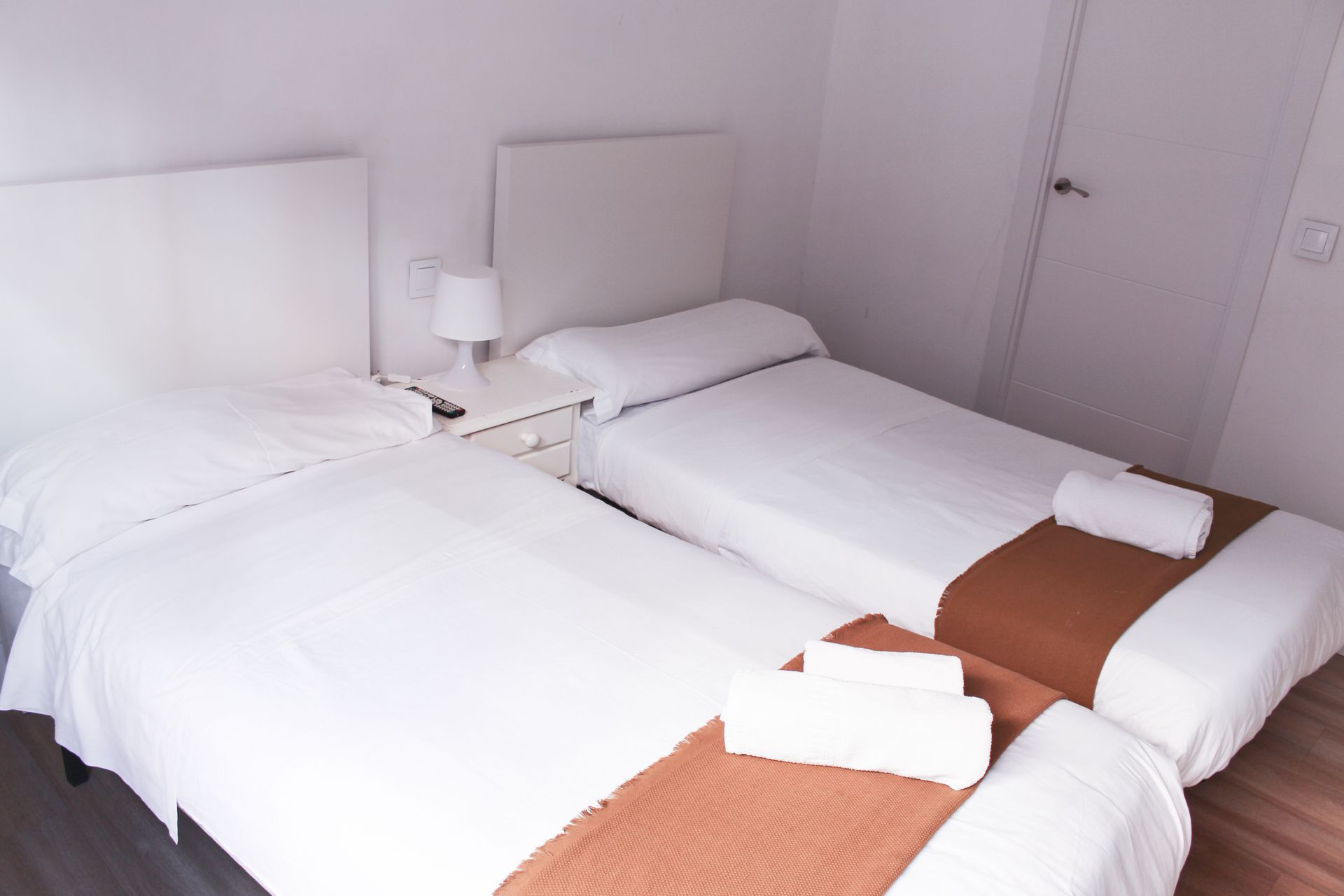 Un dormitorio con dos camas y una lámpara.