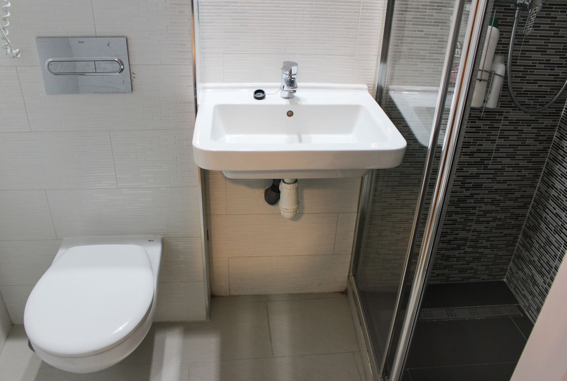 Un baño con inodoro, lavabo y ducha.