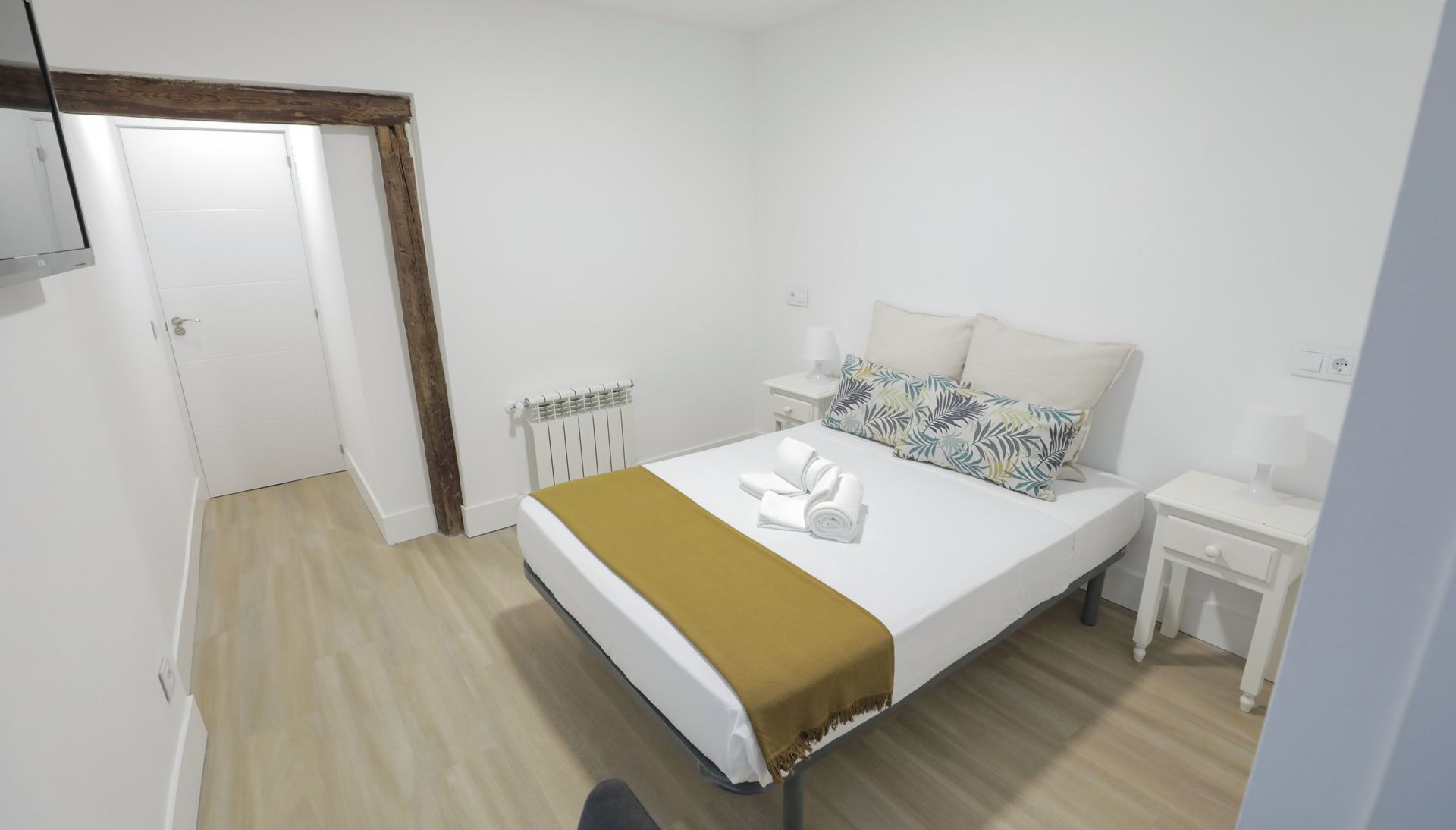 Un dormitorio con una cama, mesita de noche y televisión.