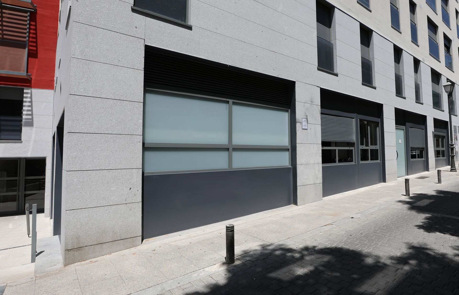 Un edificio con muchas ventanas y un edificio rojo al fondo.