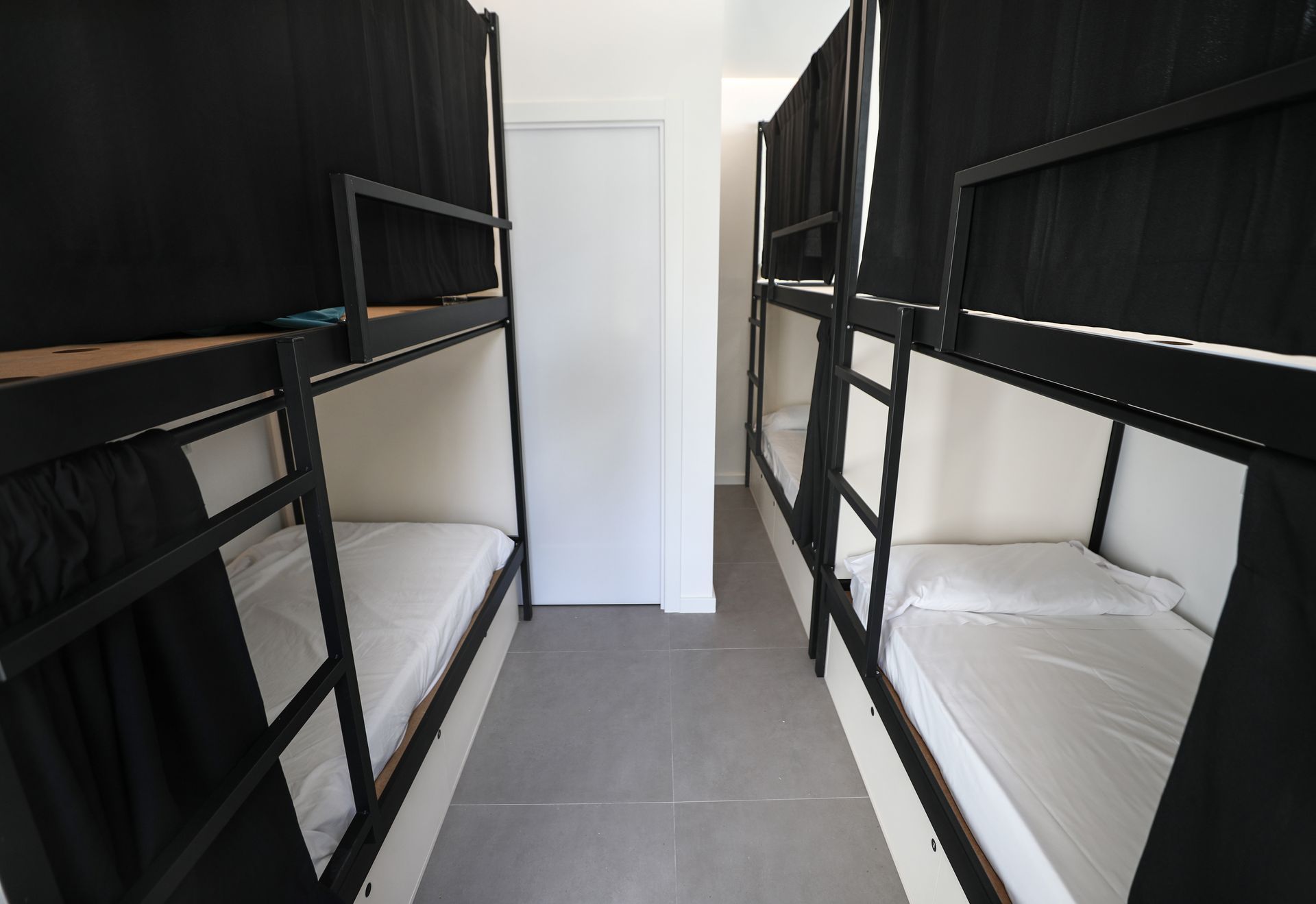 Una fila de literas en una habitación con cortinas negras.