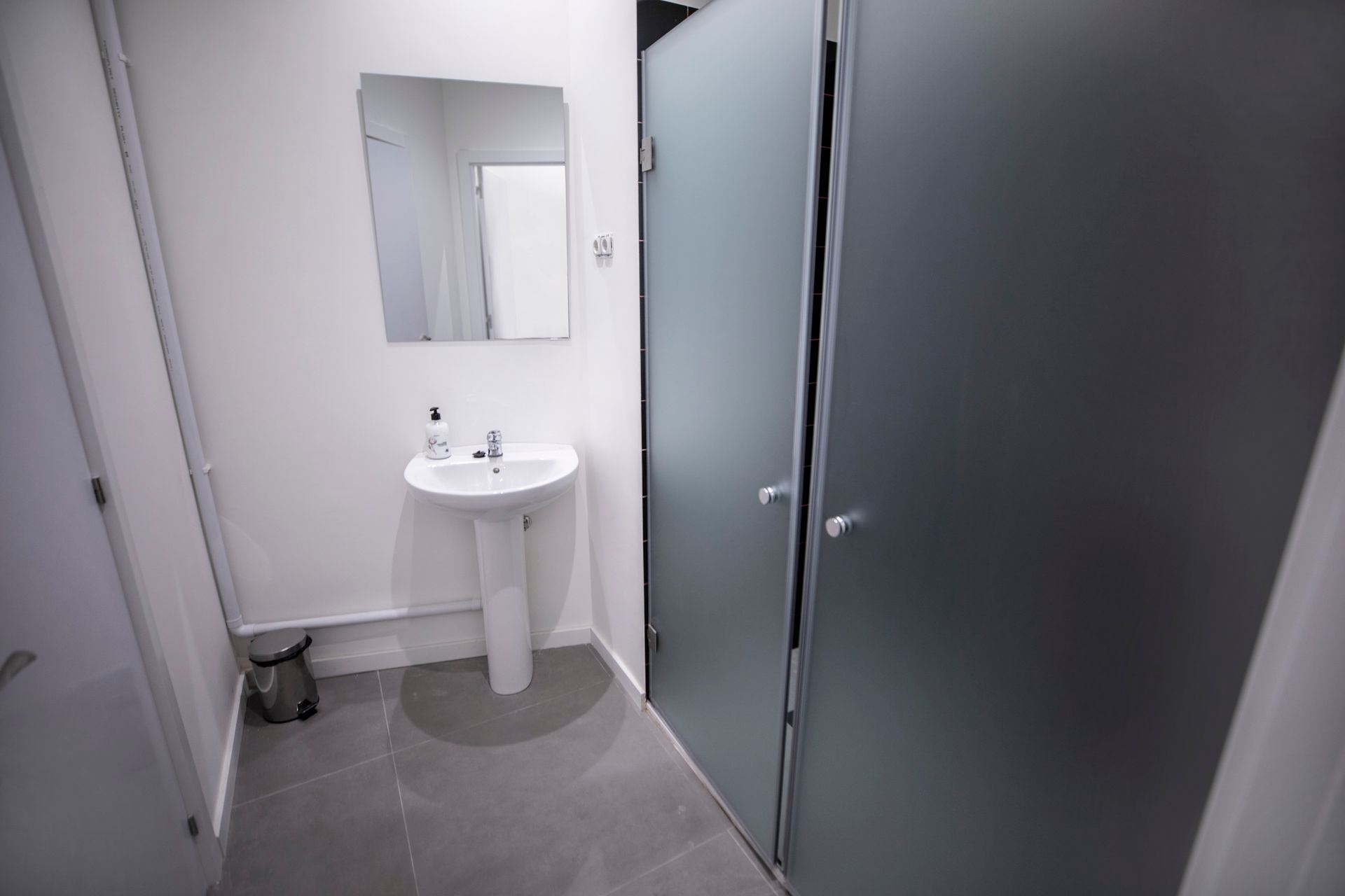 Un baño con lavabo, espejo y puertas de cristal esmerilado.