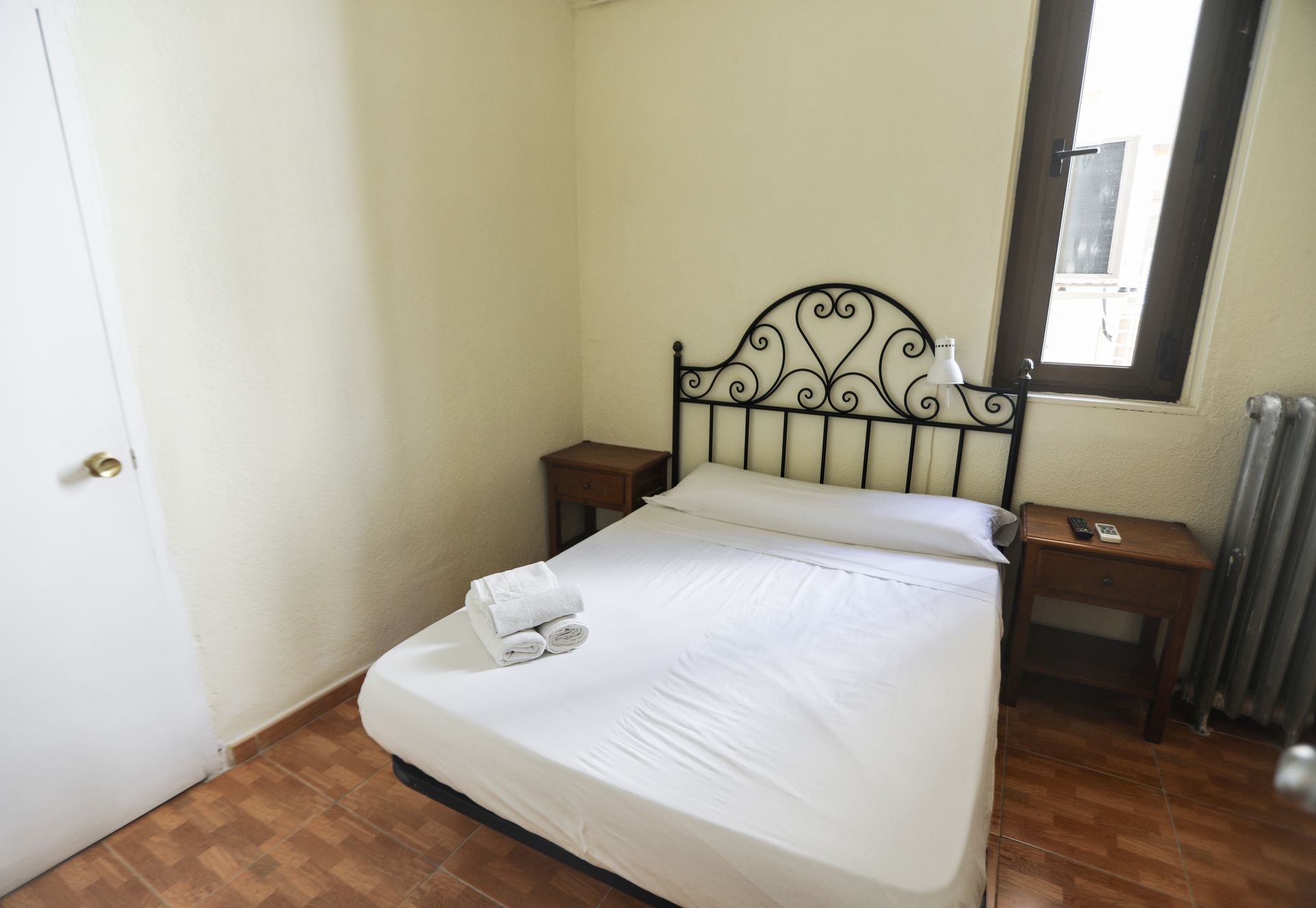 Un dormitorio con una cama, dos mesitas de noche y una ventana.