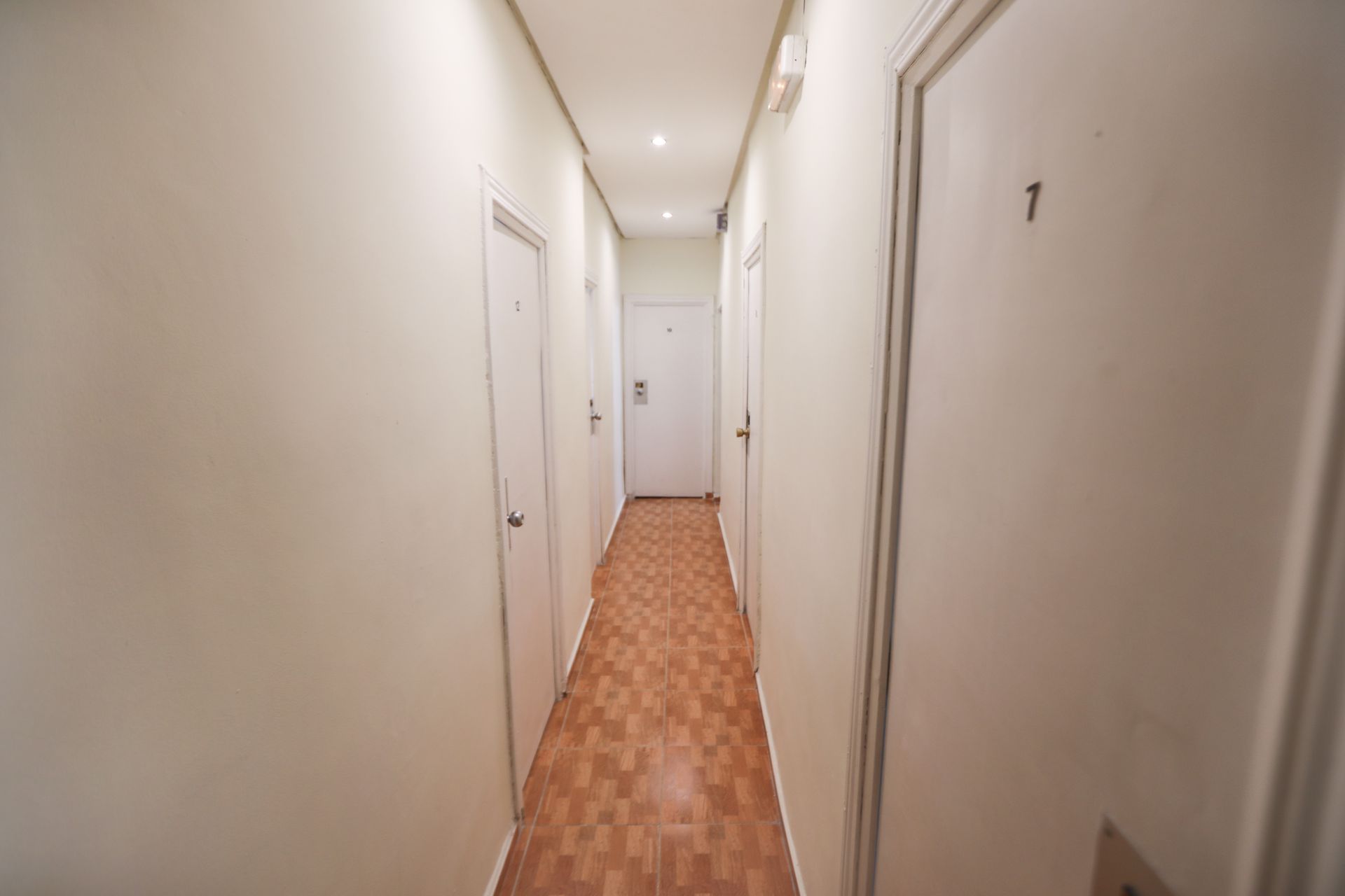 Un largo pasillo con suelos de madera y paredes blancas.