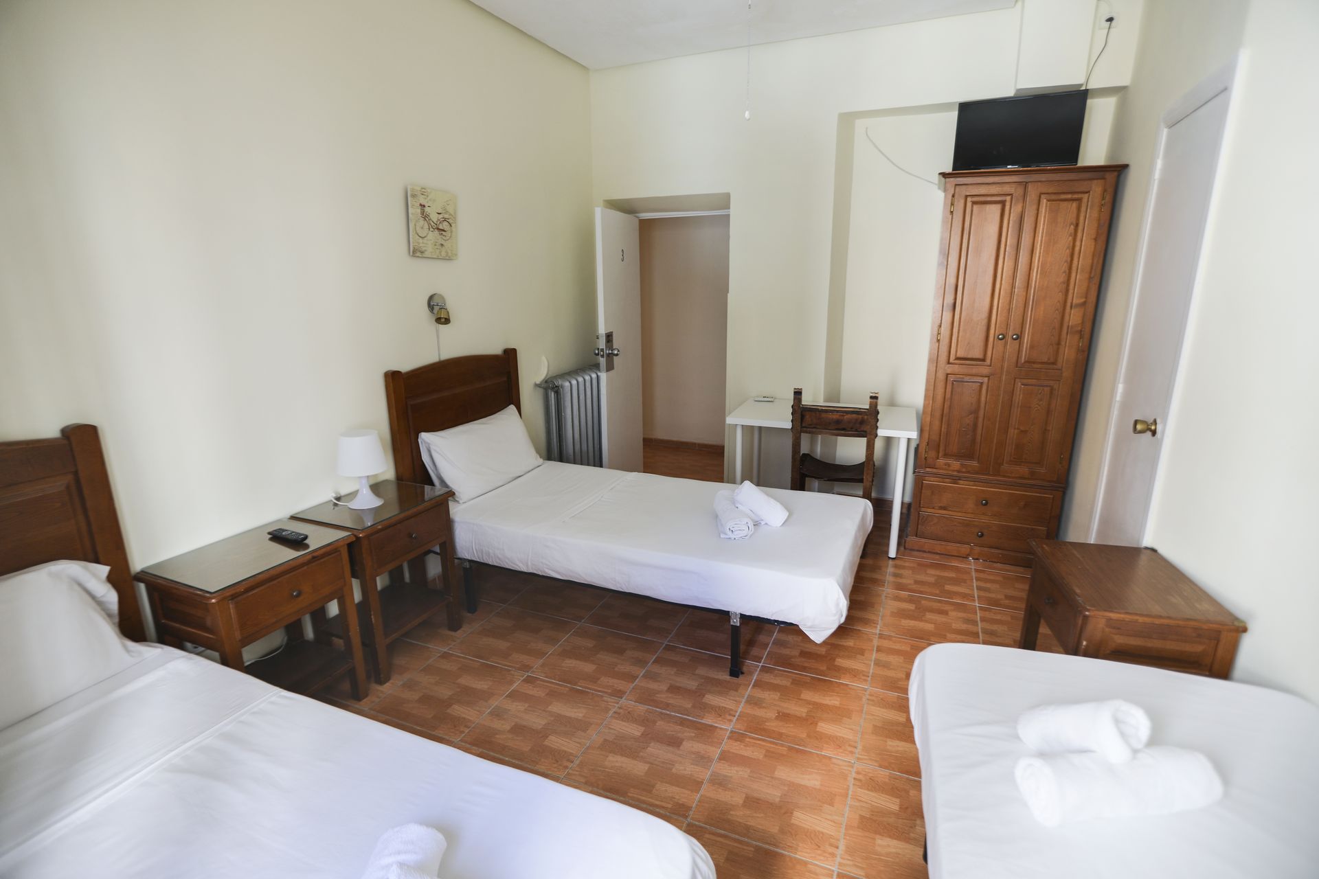 Una habitación de hotel con dos camas, un escritorio y un televisor.