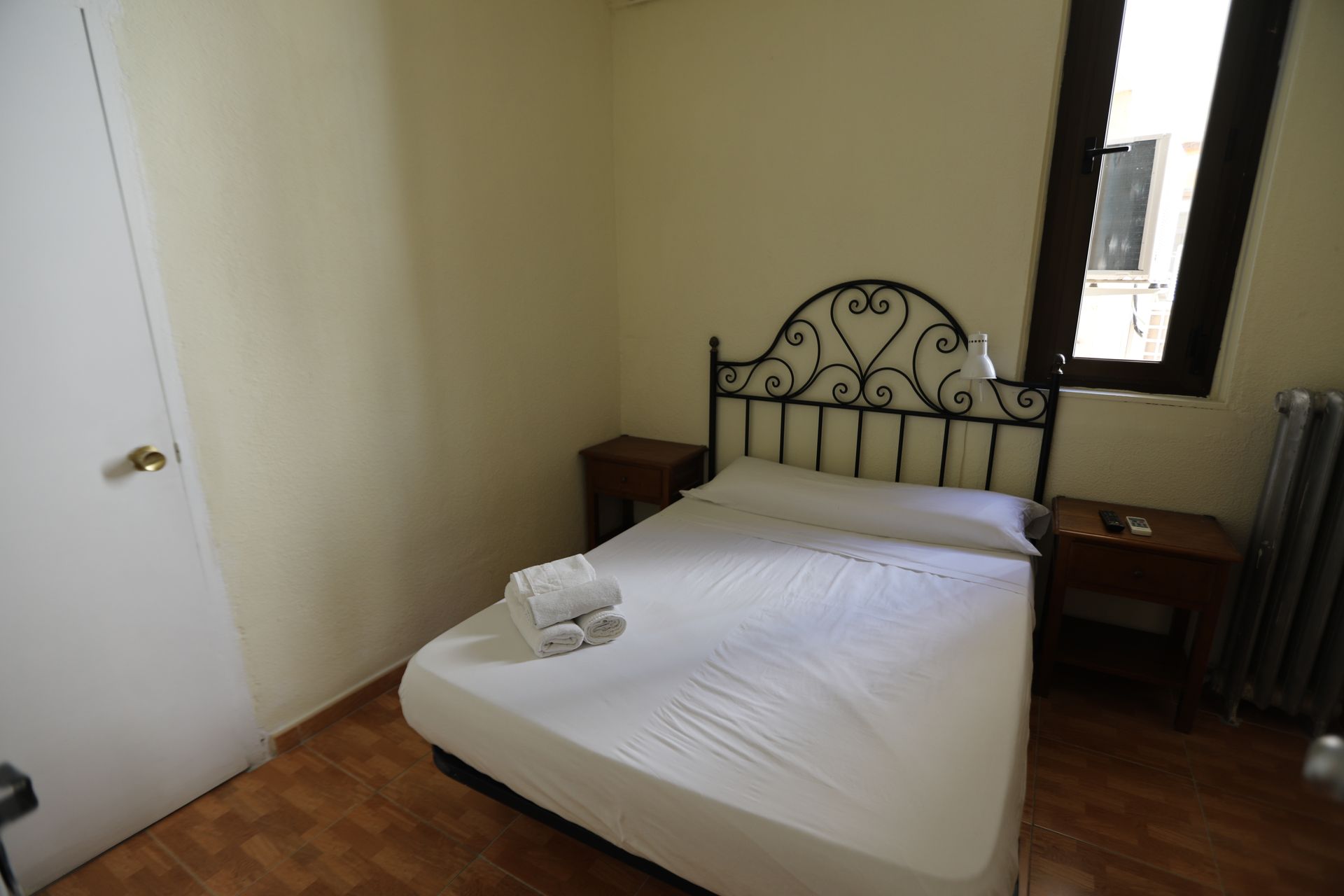 Un dormitorio con una cama, dos mesitas de noche y una ventana.