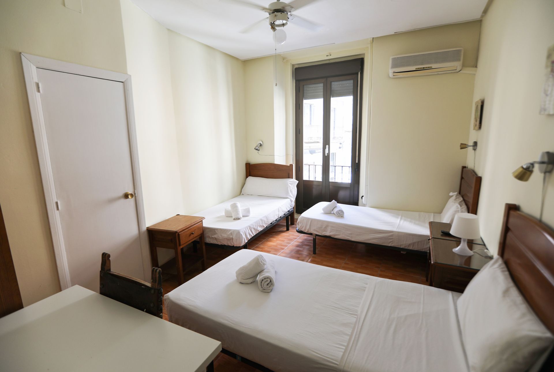 Una habitación de hotel con tres camas y un ventilador de techo.