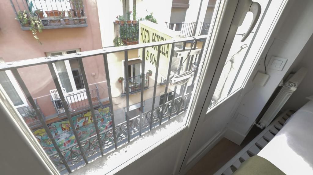 A través de una ventana se ve un balcón con barandilla de hierro forjado.