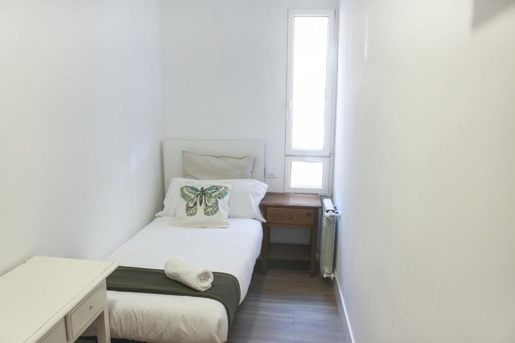 Un dormitorio pequeño con una cama individual, mesita de noche y ventana.