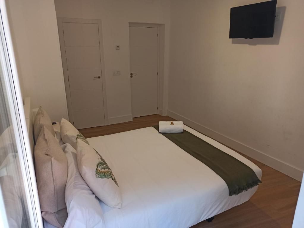 Un dormitorio con una cama grande y un televisor de pantalla plana en la pared.