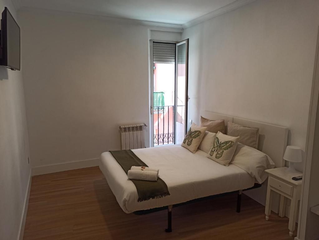 Un dormitorio con cama, mesita de noche, televisión y balcón.