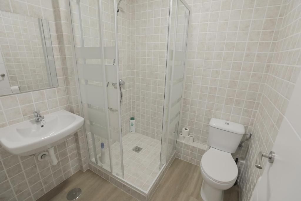Un baño con inodoro, lavabo, ducha y espejo.