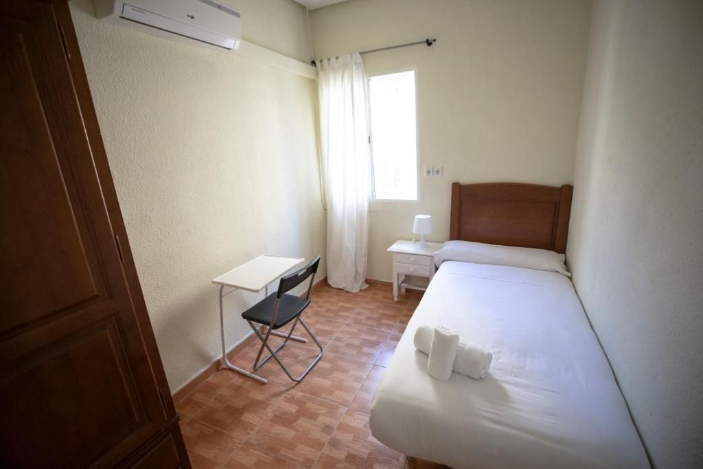 Un dormitorio con una cama individual, escritorio y silla.