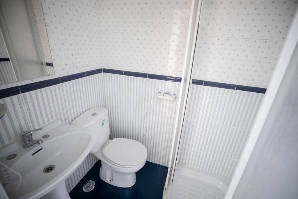 Un baño con inodoro, lavabo y ducha.