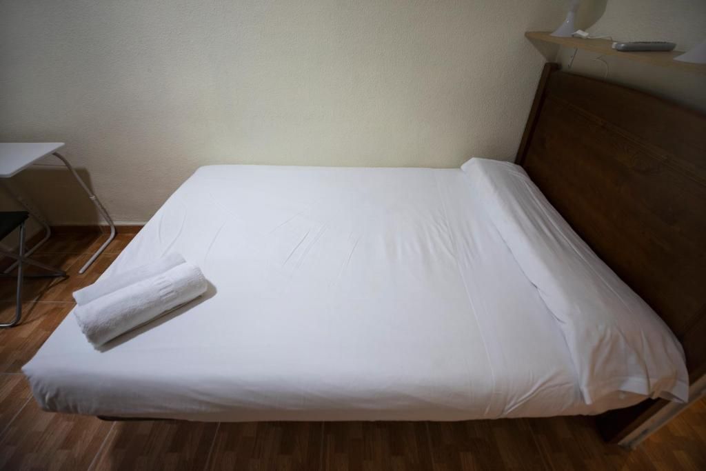 Una cama con sábanas blancas y almohadas en una habitación de hotel.
