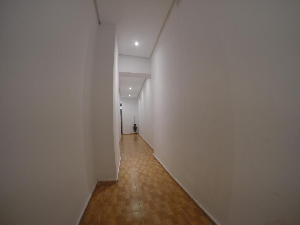 Un largo pasillo con paredes blancas y suelos de madera.