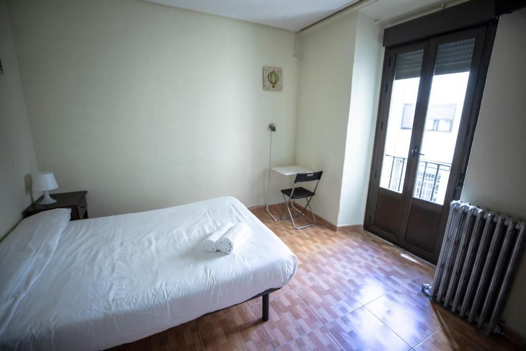 Un dormitorio con cama, escritorio, silla y radiador.