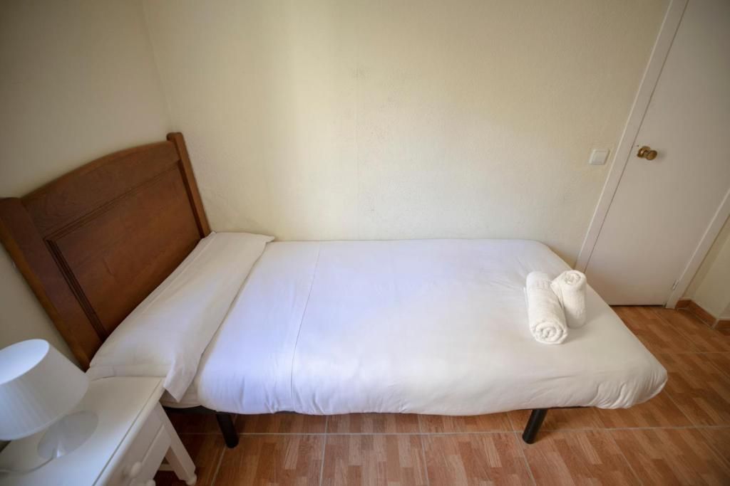 Un dormitorio con una cama individual, mesita de noche, lámpara y puerta.