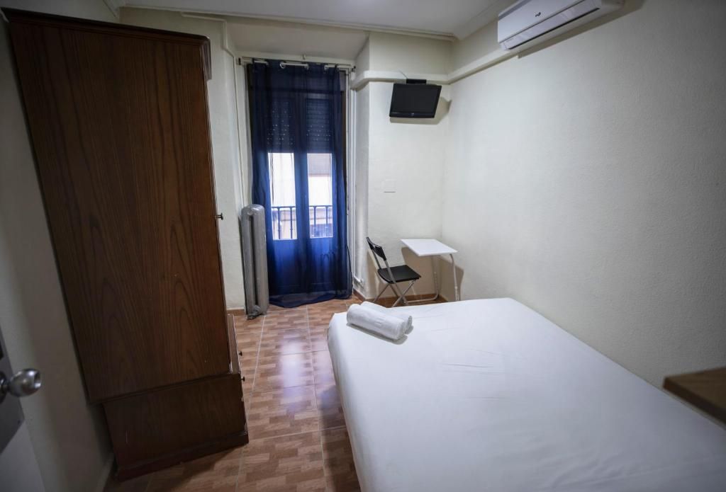 Un dormitorio con una cama, escritorio, silla y televisión.