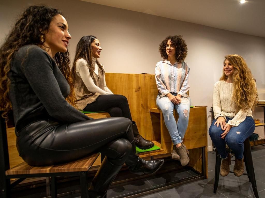 Un grupo de mujeres está sentada en bancos de madera en una habitación.