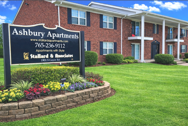 A brick apartment building with a sign in the foreground reading 