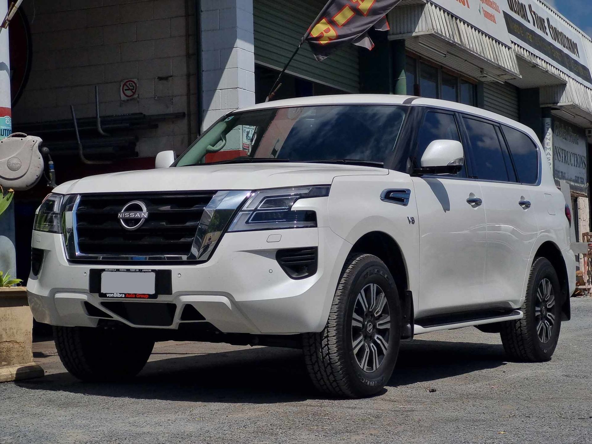 A White Nissan Patrol is Parked in Front of a Building — BJM Mechanical Mufflers & Tyres In Oxenford, QLD