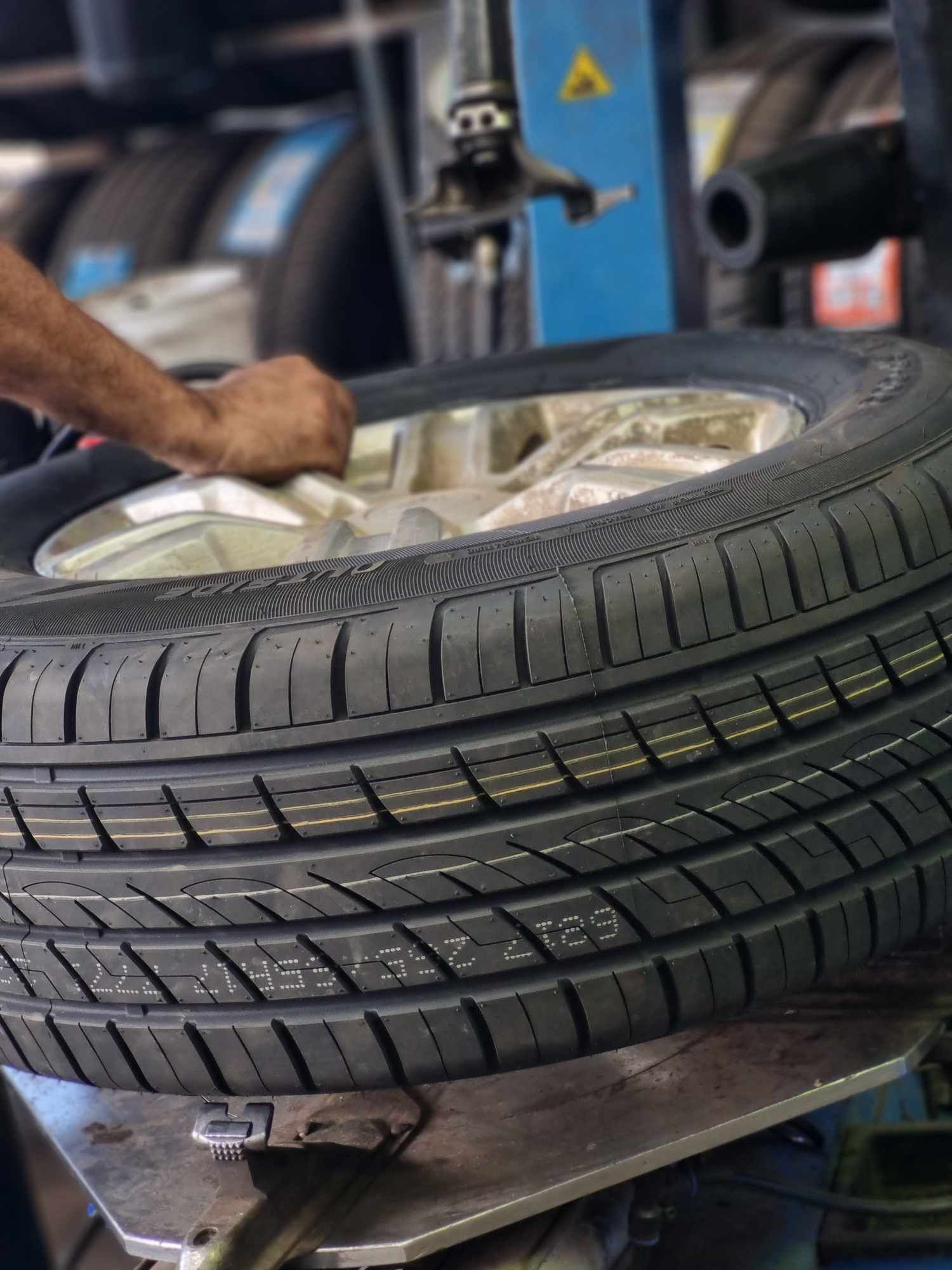 A Person is Changing a Tire on a Machine in a Garage — BJM Mechanical Mufflers & Tyres In Oxenford, QLD