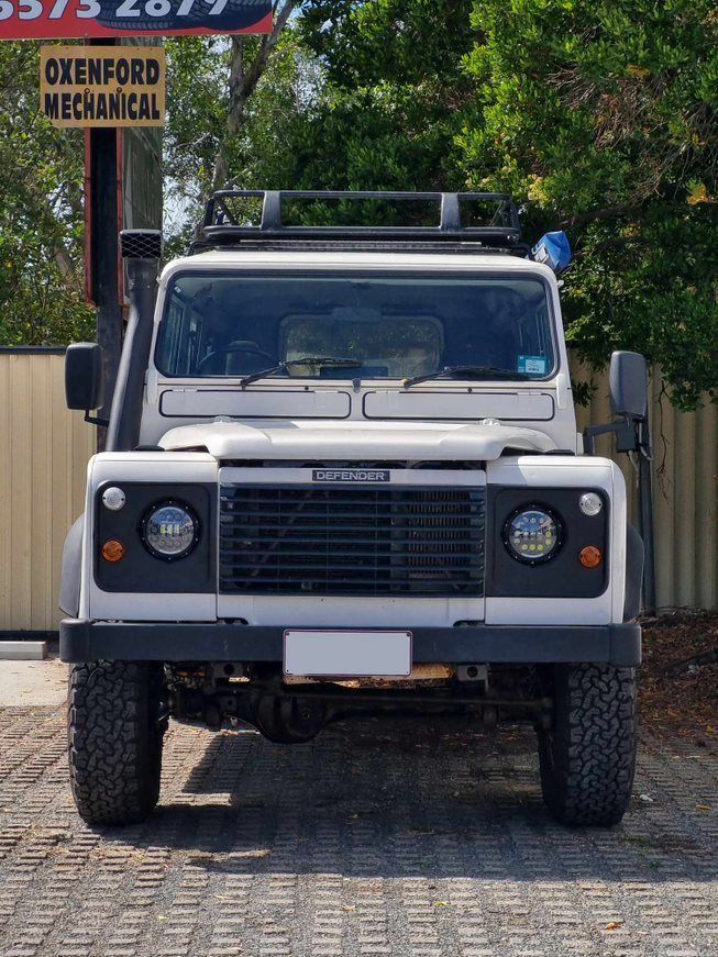 A White Defender is Parked in Front of a Sign That Says Owenford Mechanical — BJM Mechanical Mufflers & Tyres In Oxenford, QLD