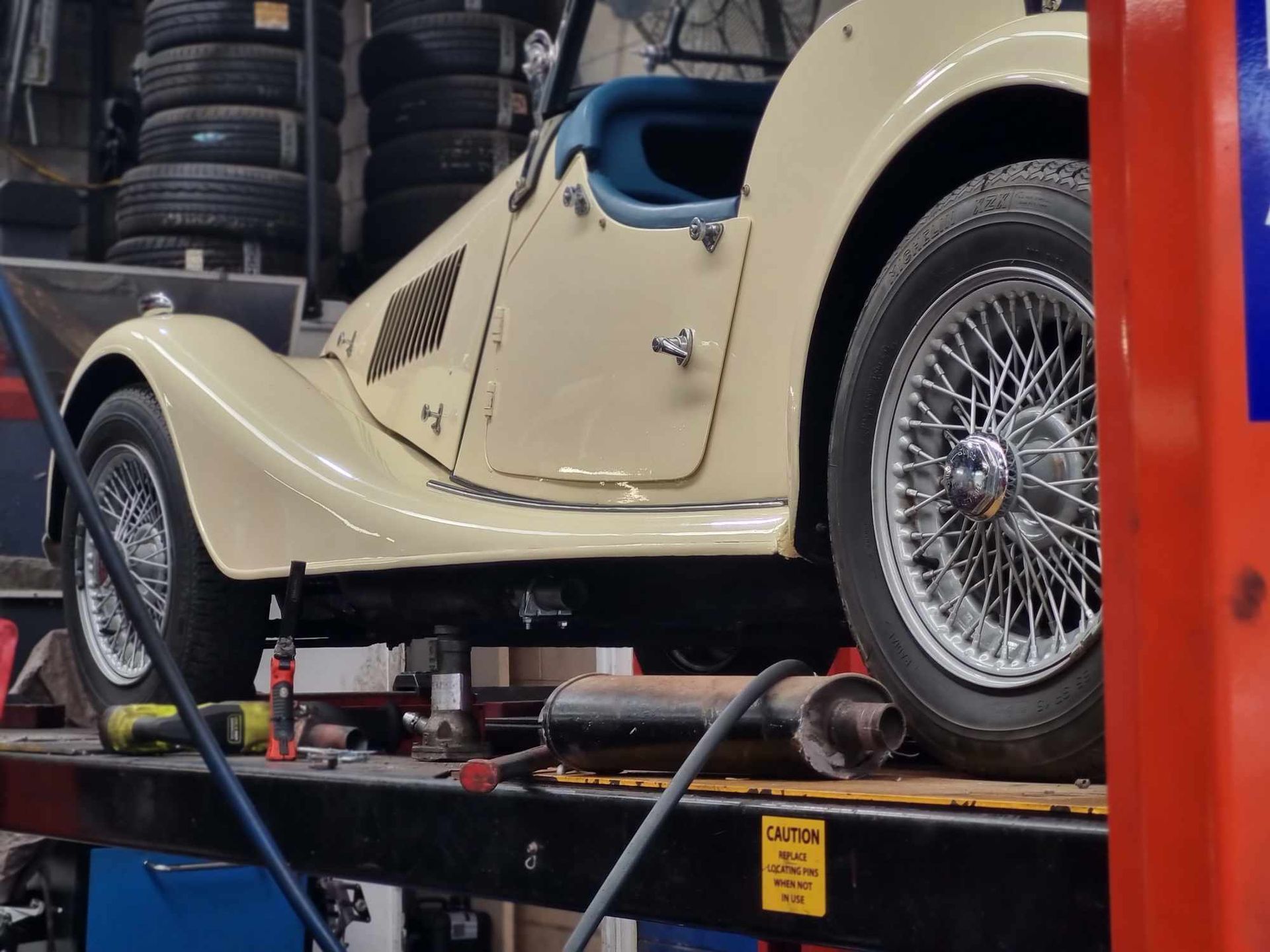 An Old Car is Sitting on a Lift in a Garage — BJM Mechanical Mufflers & Tyres In Oxenford, QLD
