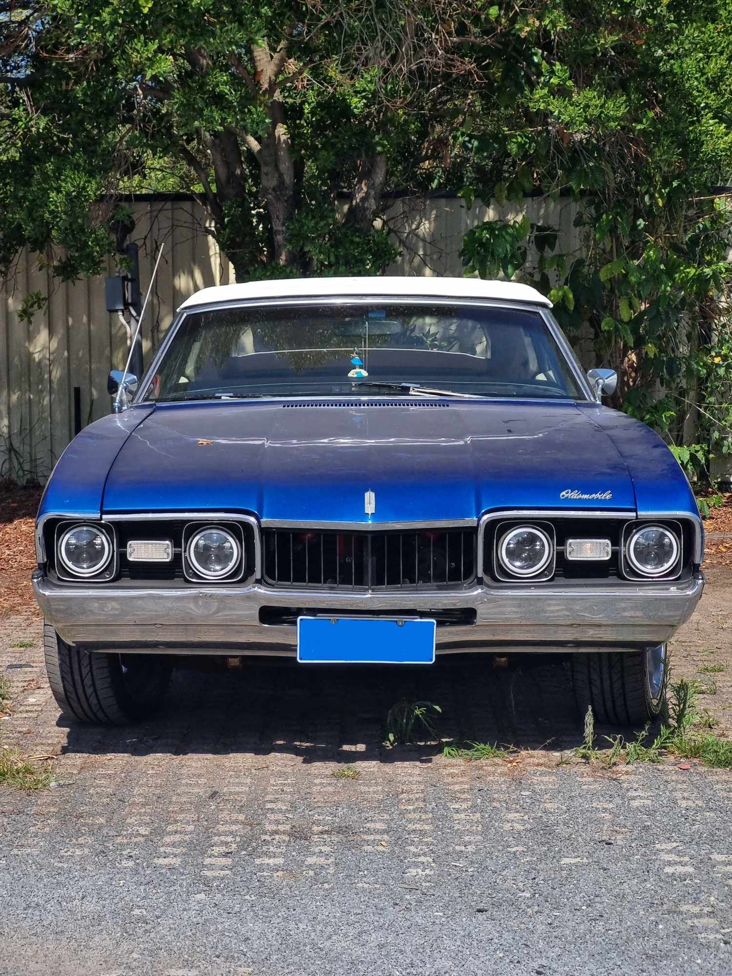 A Blue and White Car is Parked in a Gravel Driveway — BJM Mechanical Mufflers & Tyres In Oxenford, QLD