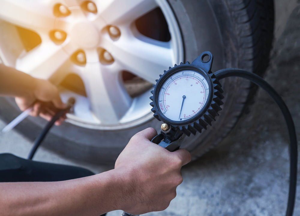 A Person is Checking the Pressure of a Tire With a Gauge — BJM Mechanical Mufflers & Tyres In Oxenford, QLD
