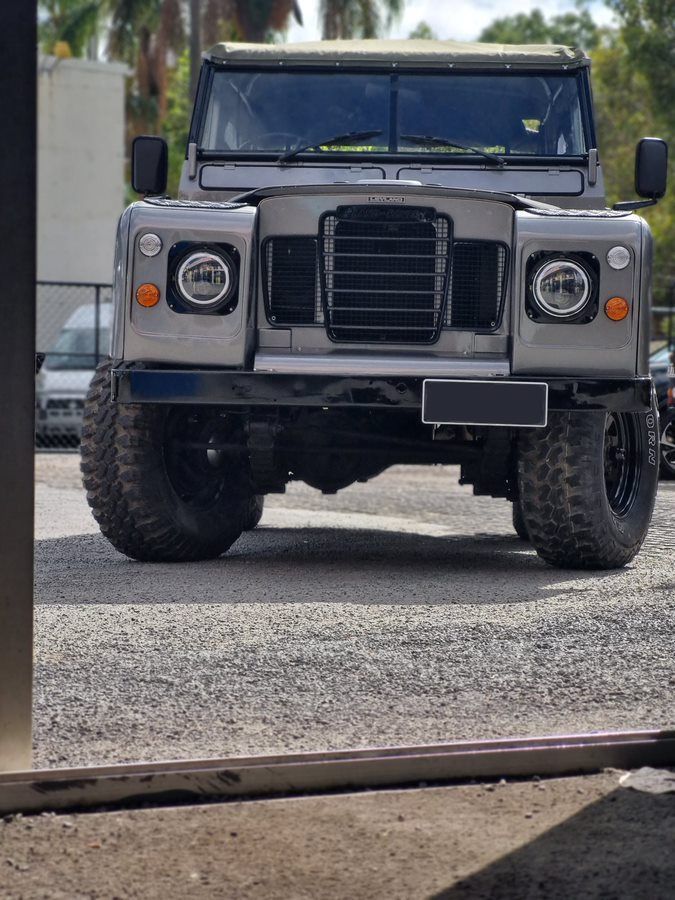 A Silver Land Rover Defender is Parked in a Gravel Lot — BJM Mechanical Mufflers & Tyres In Oxenford, QLD