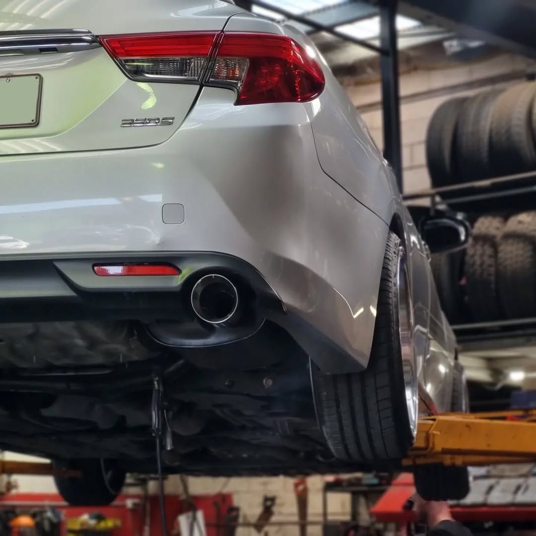A Silver Car, Rear Raised on A Lift in A Repair Shop — BJM Mechanical Mufflers & Tyres In Oxenford, QLD