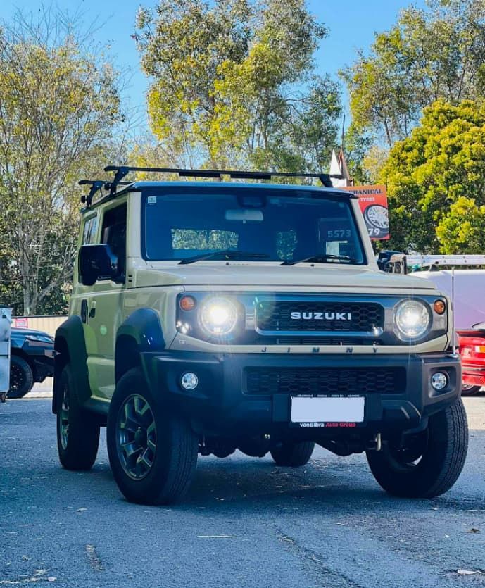 A yellow Suzuki Jimny parked on the road.