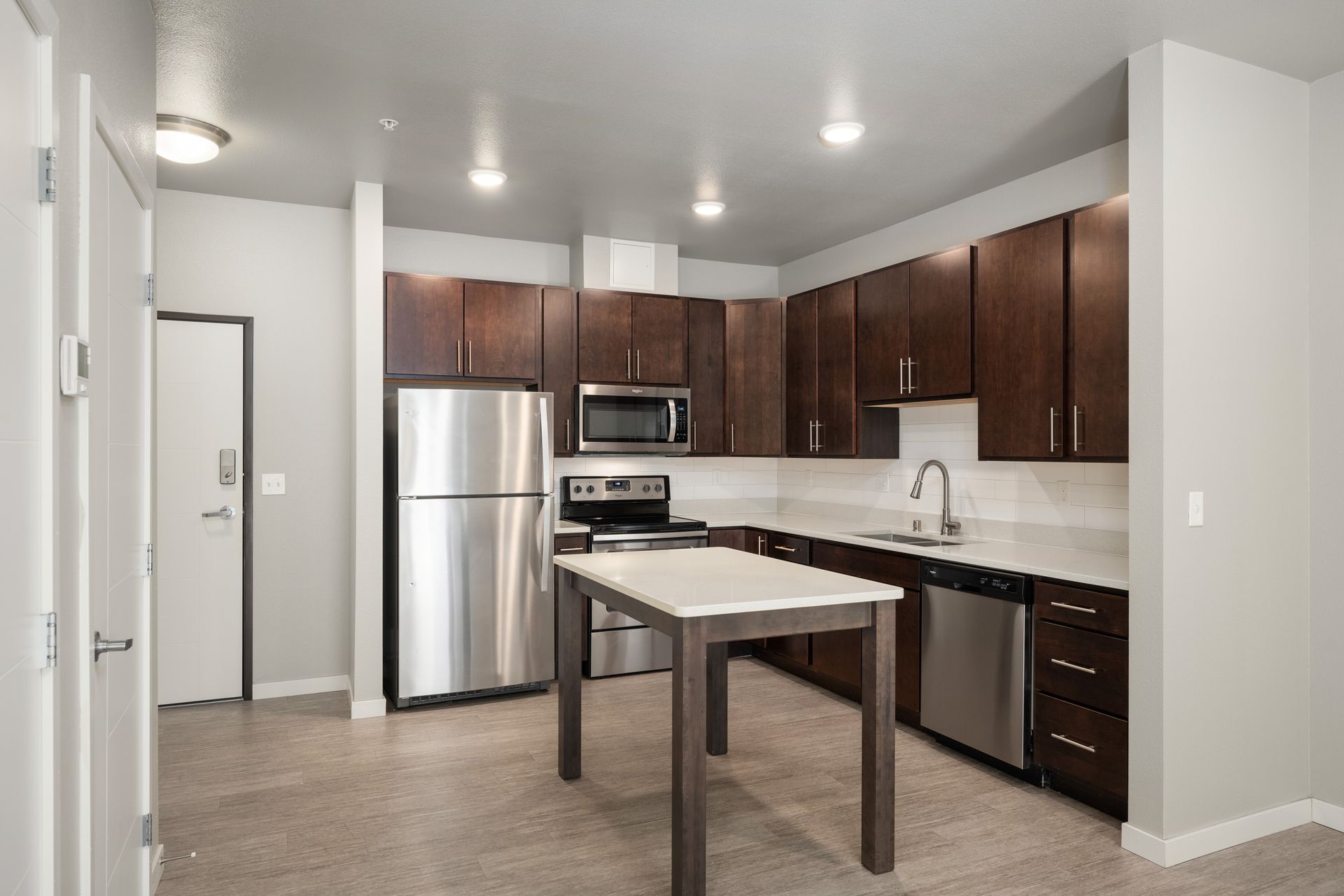 Modern kitchen with stainless steel appliances, dark wood cabinets, and an island.