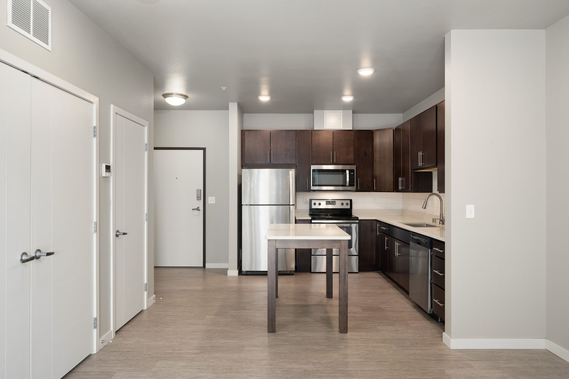 Modern kitchen with dark wood cabinets, stainless steel appliances, and a central island.