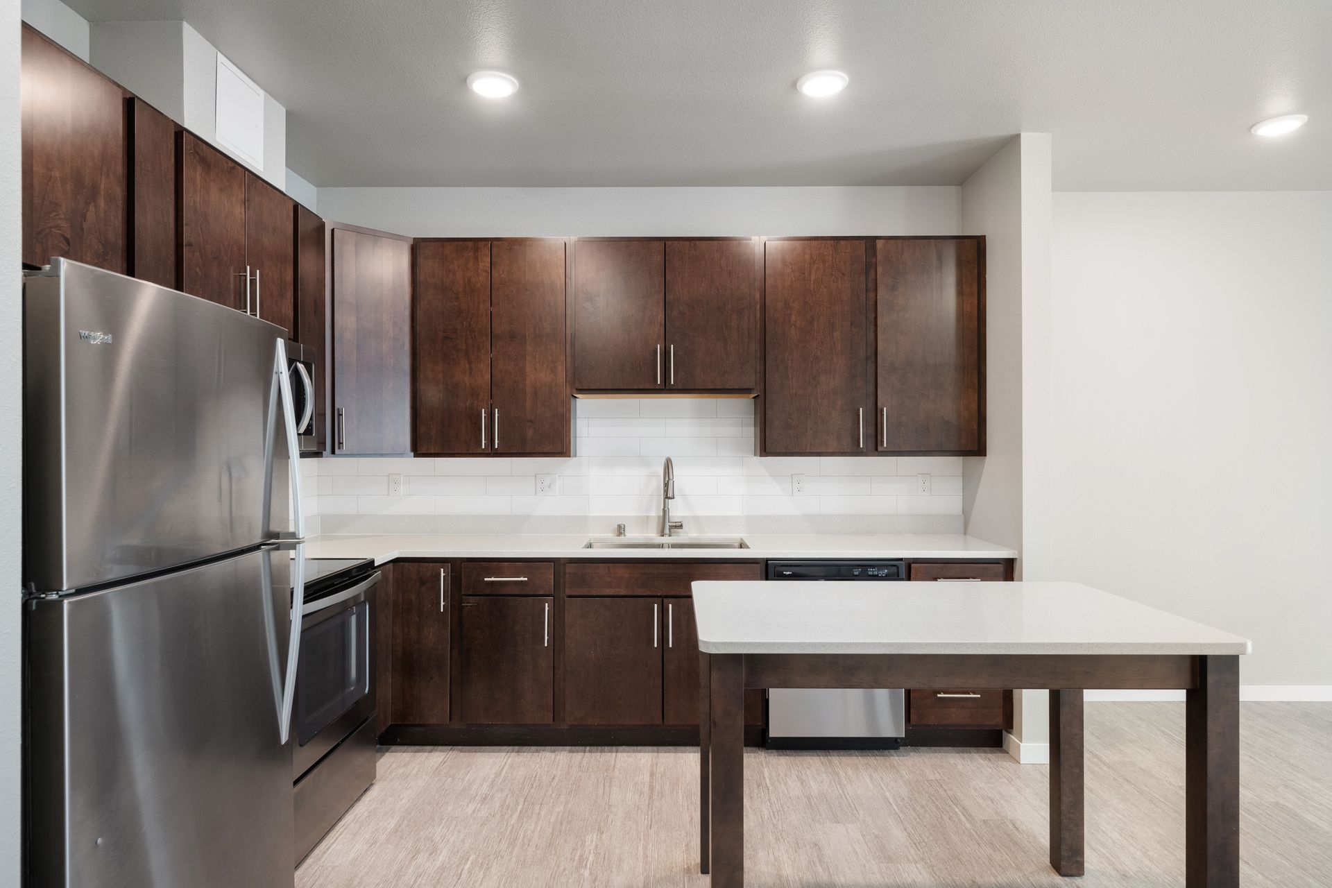 Kitchen with dark wood cabinets, stainless steel appliances, and a white countertop island.