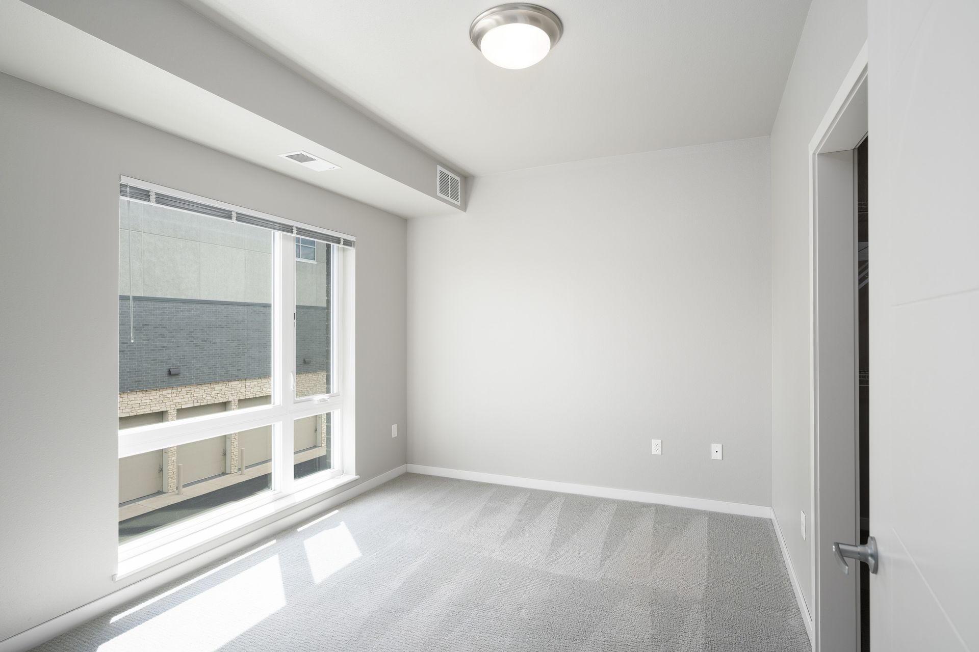 Empty room with gray carpet, walls, and window overlooking an exterior.