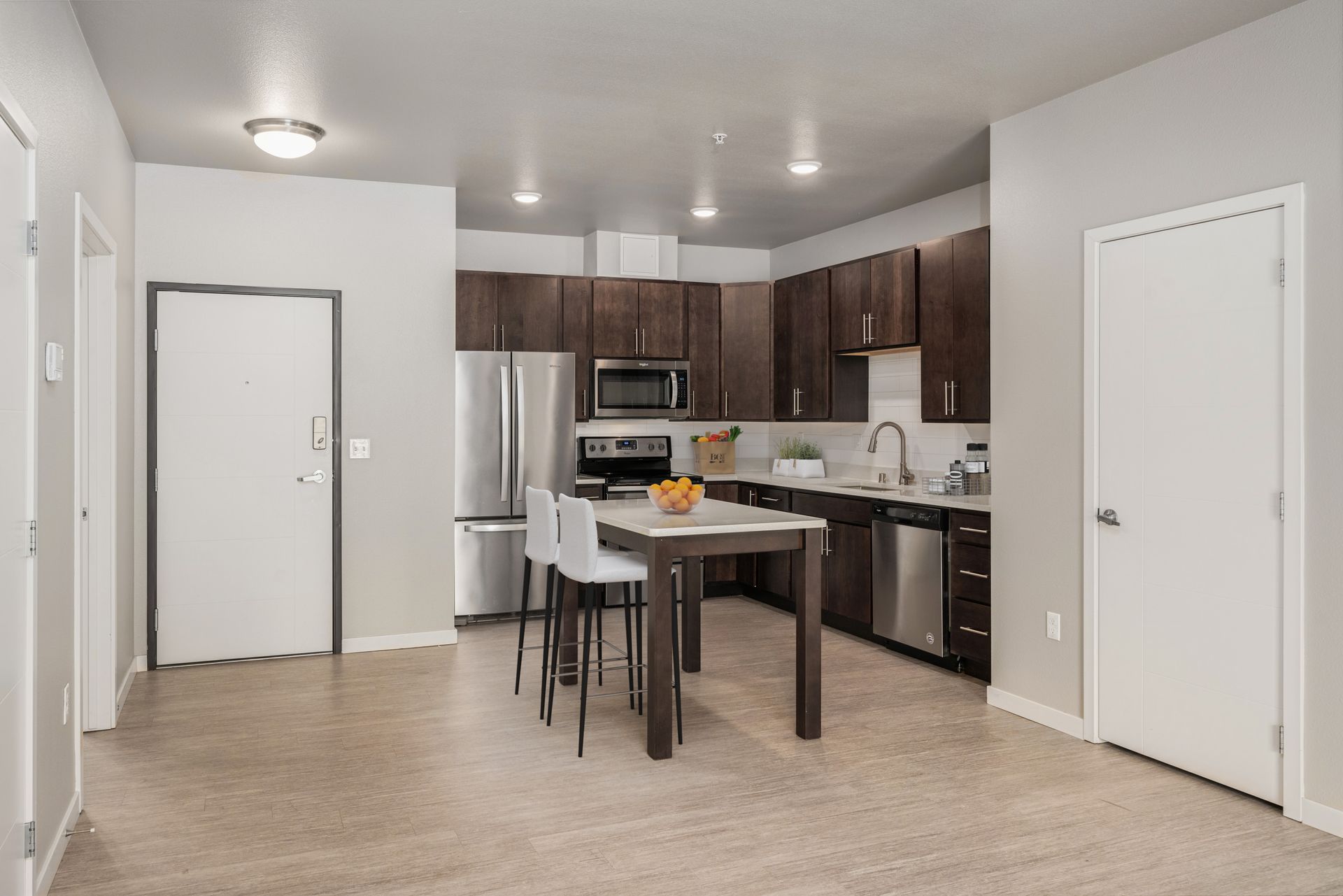 Modern kitchen with stainless steel appliances, dark wood cabinets, and a kitchen island with bar stools.