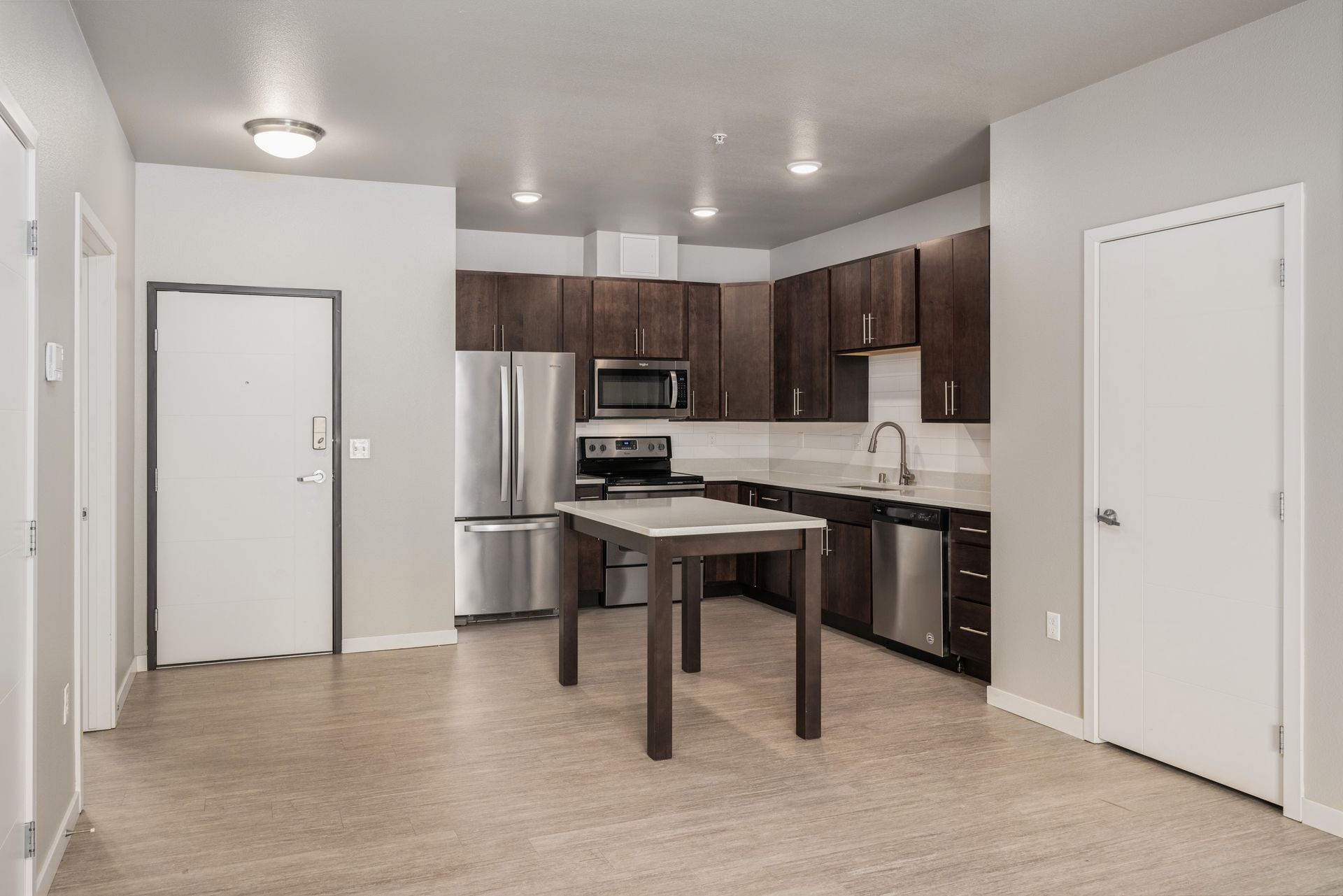 Modern kitchen with stainless steel appliances, dark cabinets, and a center island.
